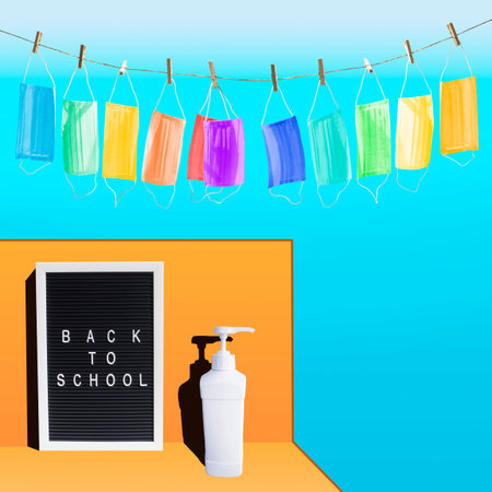 Back to school word on letter board,garland of colorful medical masks,sanitizer dispenser bottle on...