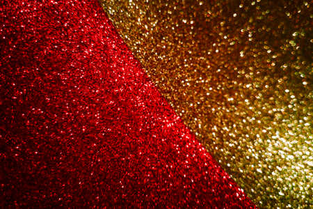 Abstract blurred background divided in half diagonally from gold and red shining, sparkling and shimmering glitter textures, dark and deep.Concept of festive Christmas or New Year background.Copy space.の写真素材