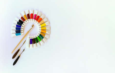 Set of 24 tubes of multicolored oil,acrylic,watercolor or gouache paints in circular pattern,brush and 2 palette knives,in shape of letter P on white background.Arts, school and education.Copy spaceの写真素材