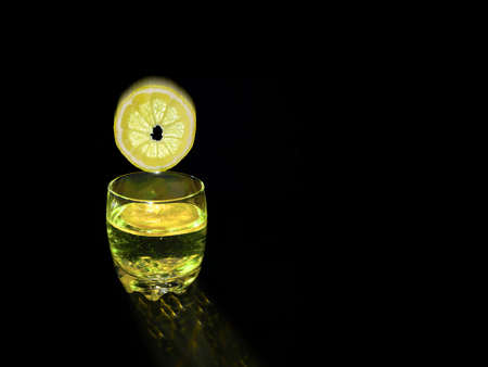 Lemon circle falling into clear glass with alcoholicの写真素材