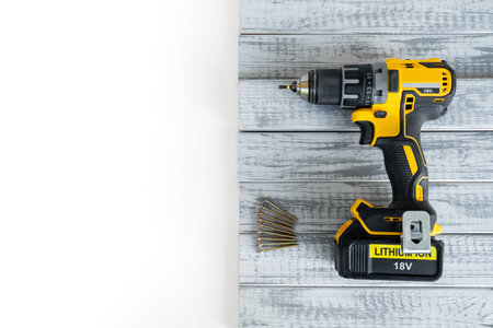 Close-up no name black yellow electric cordless screwdriver, not new, number of self-tapping screws...