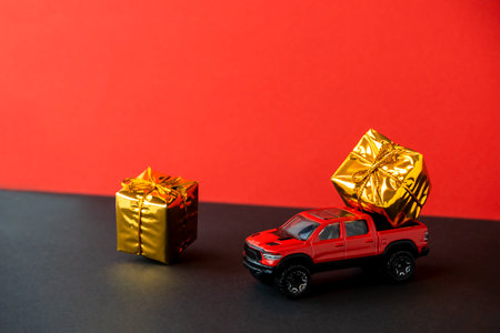 Red toy car SUV gift box on trunk close-up,two-tone black background,levitating festive packaging,bow.New Year,Christmas holiday automobile concept.Dealership prize lottery.Copy space.Auto deliveryの写真素材