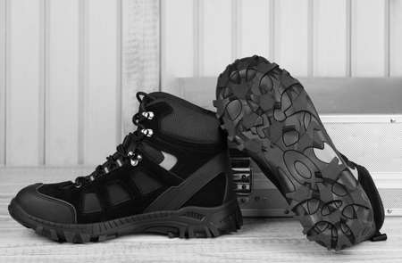 Close-up pair black textile work boots for safe winter with steel cap,boot view of non-slip material sole on gray wooden background and metal tool box.Comfort flexibile safety workers concept,rooferの写真素材