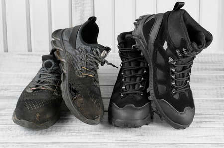 Close-up 2 pairs old and new black textile work boots for safe winter with steel toe,non-slip material sole on gray wooden background.Changing worn torn shoes to fresh,contrast concept.Selective focusの写真素材