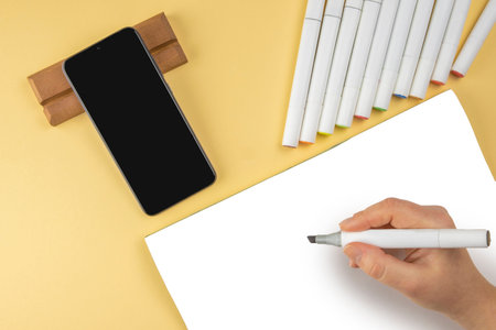 Flatly set of two-sided markers for sketches,white paper album sheet,black smartphone on wooden...