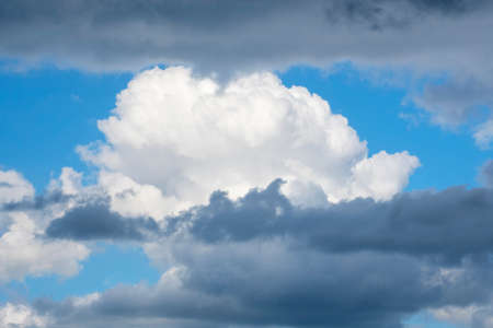 Wild stormy beautiful blue sky with white gray contrasts. Fluffy cumulus clouds in different layers. Concept of struggle between good and evil, bad ot fine weather, wind change in cyclone. Copy space.の写真素材