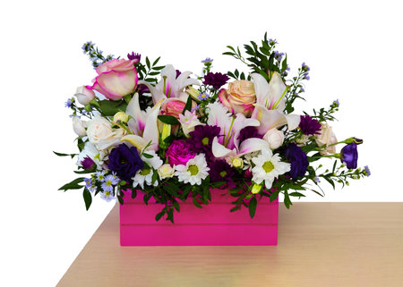 Fresh flowers in pink wooden box, bright bouquet on white backdrop on light table corner. Floral composition of summer plants arranged stylishly with taste. Celebration or birthday gift. Copy space.の写真素材