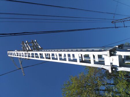 Power lines on the railway. Electric railway equipment. Photo close-up of industrial infrastructure against a bright blue sky. Wires supply electricity to electric trains.の写真素材