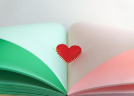 Delicate postcard in pastel colors. An open book with pale green leaves with a red glass heart in the center of the pages. Congratulations on your wedding and Valentine's Day. Space for text.の写真素材