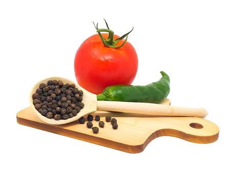 Closeup isolate: black pepper, juicy red tomato, green chili pepper. Fresh vegetables and spices on a wooden cutting board on a white background. Menu concept, ingredients for salad, healthy food.の写真素材