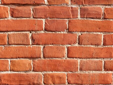 The texture of red antique brick. Background of old red brick wall texture with deterioration from age. The brick wall is lit by the bright sun.の写真素材