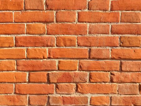 The texture of red antique brick. Background of old red brick wall texture with deterioration from age. The brick wall is lit by the bright sun.の写真素材