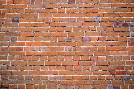 The texture of red brick with bright splashes of colored paint. Brick wall background. Textured bricks. Background of red brick wall texture.の写真素材