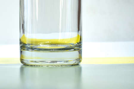 The lower part of the transparent glass on a gray-yellow background. A closeup of the bottom of one transparent glass bottle. Refraction and reflection of light. Selective focus.の写真素材