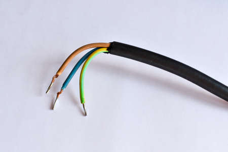 Three wires (plus, minus and earthing). Three-wire electric wire. The power cable is cut, with the output of three copper wires and shielded by a drain wire. Triple cable on a white background.の写真素材