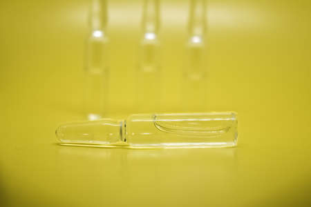 Transparent medical ampoules close-up, selective focus. A lot of glass ampoules on a yellow background. Medical concept.の写真素材