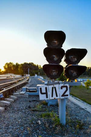 Railway traffic light and rails on the background of the setting sun. Railroad tracks at sunset.の写真素材