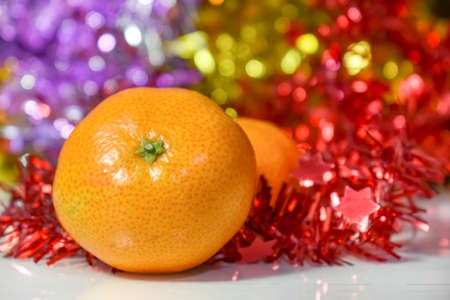 Christmas composition on colorful bokeh background. Mandarins against a background of blurry defocused multicolored lights and tinsel. Concept for Christmas, New Year. Space for text. Selective focusの写真素材