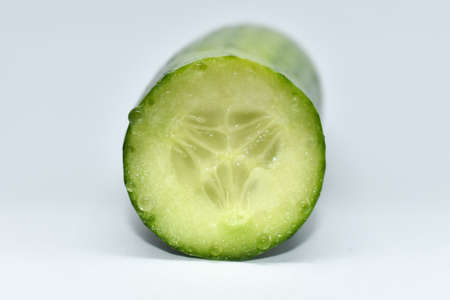 Green cucumber. Sliced ââpiece of fresh cucumber on a white background. Cucumber juice is released when cut. Single cucumber or zucchini. Vegetarian, healthy diet food. Ingredient for salad.の写真素材