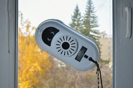 Robot for cleaning windows and ceramic tiles against a background of a window and an autumn...