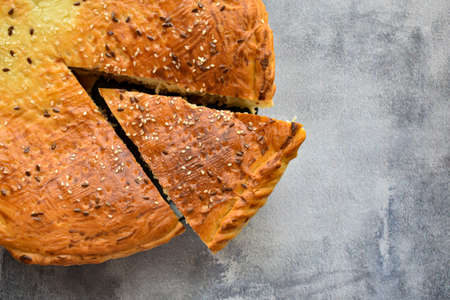 Freshly baked traditional meat pie on the background of a concrete table. Top view, place for text. Delicious homemade pie sprinkled with sesame seeds with a cut piece on a concrete background.の写真素材