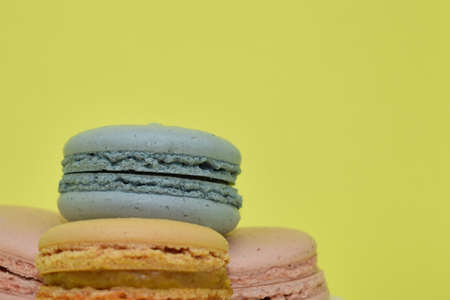Multicolored macaroons in the form of a tower on a yellow background. Colorful greeting card with delicious almond cookies. Sponge cakes on top of each other. Spaces for text, copy space.の写真素材