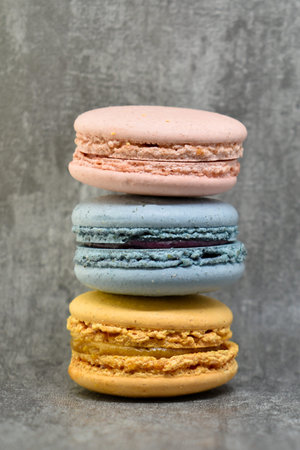 Multicolored macaroons cakes in the form of a tower on a dark gray concrete background. Macaroons on...