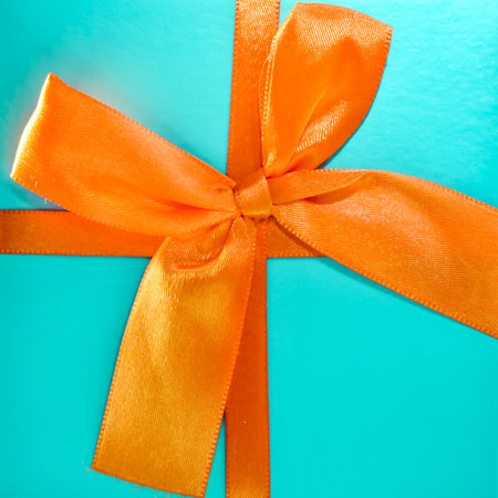 Light blue gift box with orange bow close-up. Greeting card. space for text, top viewの写真素材