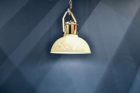 modern chandelier hanging on wall background. Subdued light of lamp in evening in room. Shadows on wall. pendant lamp on background of blue painted wall. Modern interior background. Selective focusの写真素材