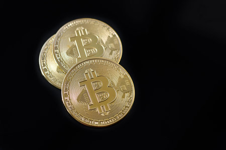 Gold Bitcoin coins on black background. Three gold bitcoin coins. Bitcoin close up. Golden bitcoins....