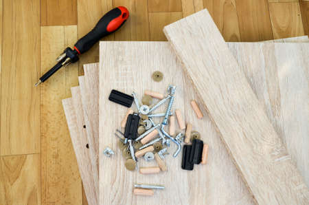 Chipboard sheets, tools and parts for assembly of cabinet furniture. Self-assembly of furniture at home. details of bedside table are spread out on floor. tool for assembling glued wood materialsの写真素材