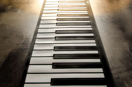 Close-up of a flat piano keyboard, top view. Piano keys on a textured concrete background. soft toning. warm soft light Jazz music styの写真素材