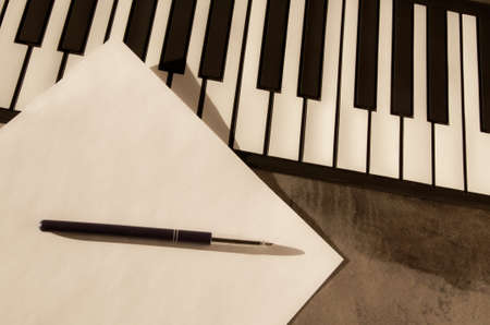 Piano keyboard, pen and blank paper. The concept of composing music, songs, creativity, learning. Learning to play the piano.の写真素材