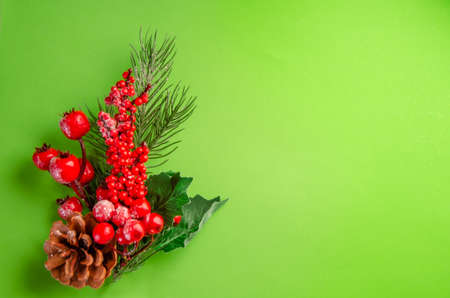 Christmas decor on a green background. A branch of a Christmas tree with decorations, red berries, cones. New Year's composition. space for textの写真素材