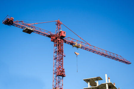 Erection crane at the construction site of a multi-storey building against the backdrop of a blue...