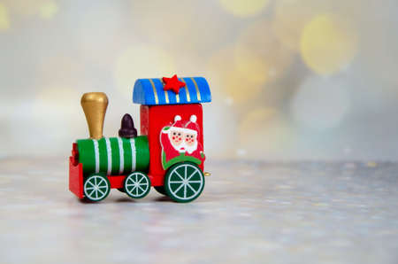 Christmas train on a background of bokeh of golden lights. Santa Claus red wooden toy train. Selective focus. Merry Christmas and Happy New Year greeting card. space for text.の写真素材