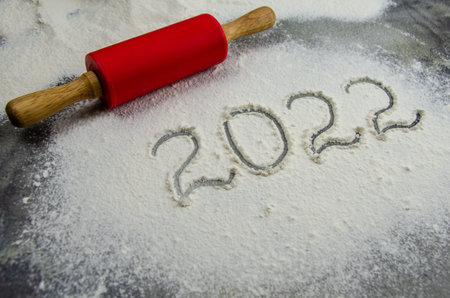 2022 sign is painted on flour. inscription 2022 is made of flour on black concrete background. Top...