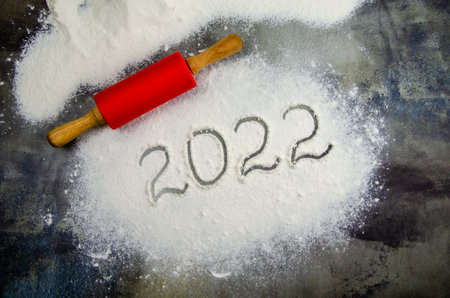 2022 sign is painted on flour. inscription 2022 is made of flour on black concrete background. Top view, flat lay, space for text. rolling pin, flour and numbers 2022. Christmas culinary backgroundの写真素材