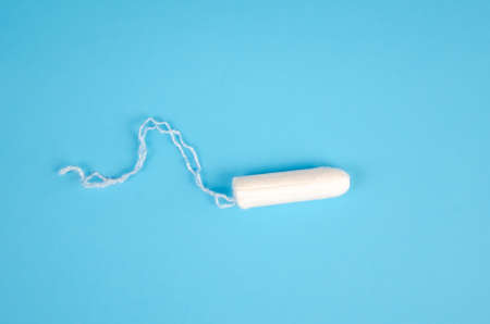 One hygienic feminine tampon on a blue background. white cotton swab for women, protection during menstruation. Feminine hygiene.の写真素材