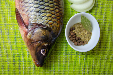 Fresh fish, sliced onion half rings and spices on a kitchen napkin. Raw carp with peppers and onions. Ingredients for cooking River fish.の写真素材