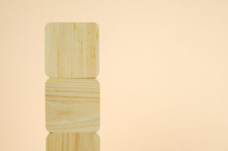 empty wooden cubes are stacked in a tower shape, one on top of other. blocks are vertically lined on beige background. concept of business, interaction, growth. Template for design, space for textの写真素材