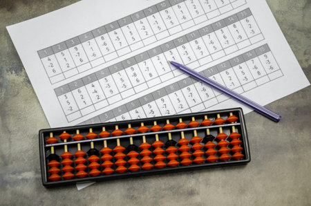 Abacus for mental arithmetic on the background of a sheet of paper with examples for calculation....