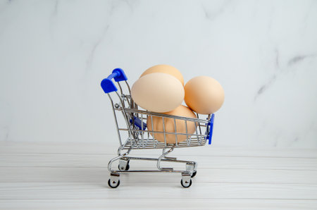 grocery cart filled with chicken eggs. basket, supermarket trolley with eggs. concept of preparing for Easter, buying food, supporting agriculture. Space for textの写真素材