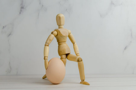 wooden man holding a chicken egg. the mannequin got down on one knee, holding the egg. creative...