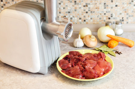 Electric meat grinder on the kitchen table next to the ingredients for cooking. Preparing to cook...