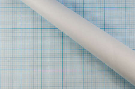 Blank unfolded sheet and roll of graph paper. Background for sketching, painting, drawing. Roll of blue graph paper on sheet of graph paper.の写真素材