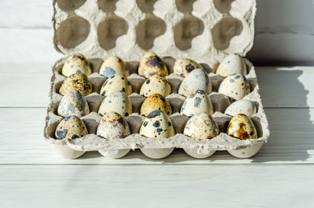 Quail eggs in eco-friendly packaging made from recycled paper, on white wooden table background
