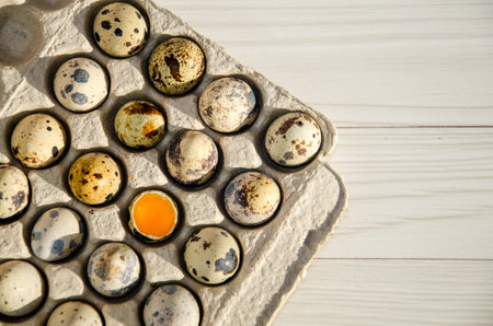 Quail eggs in a cardboard box close-up, texture. eco-friendly egg tray. One egg is broken.の写真素材