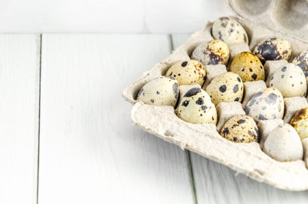 Quail eggs in eco-friendly packaging made from recycled paper, close-up on a white wooden table...