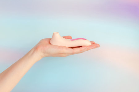 pink vacuum wave vibrator for clitoral stimulation in an elegant female hand. Sex toy for women on a light blue background. A product from a sex shop, for adults. space for textの写真素材